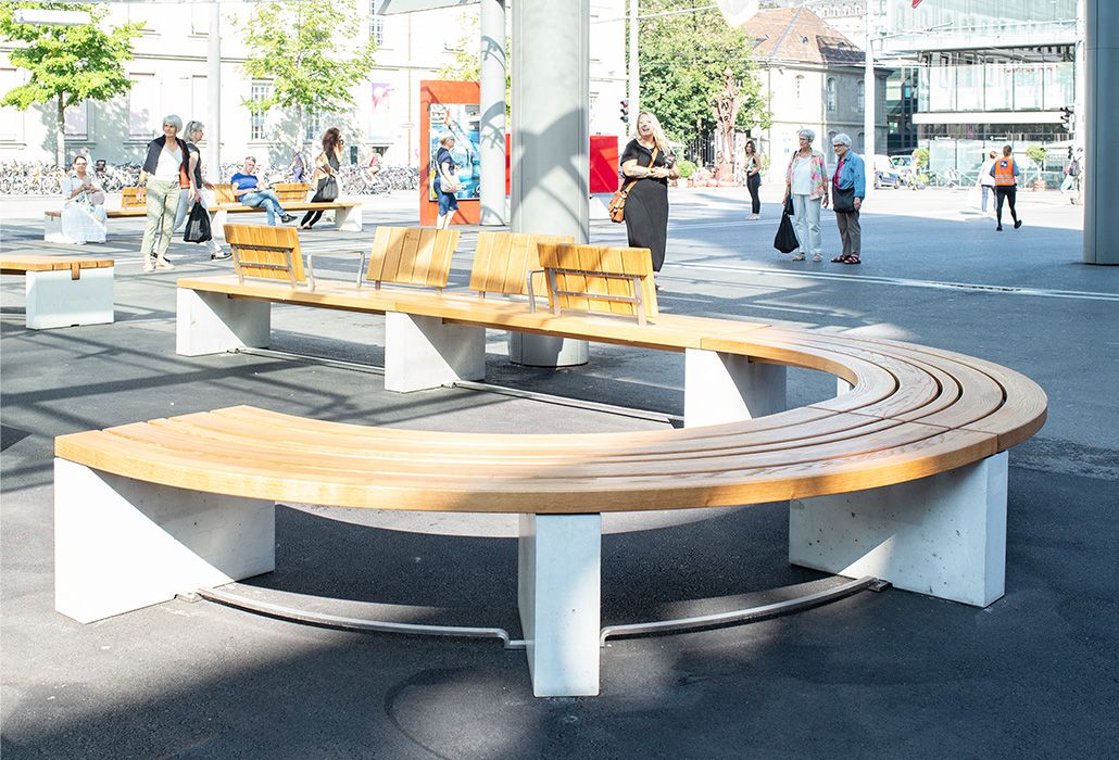 A long, curved wooden bench in a public space